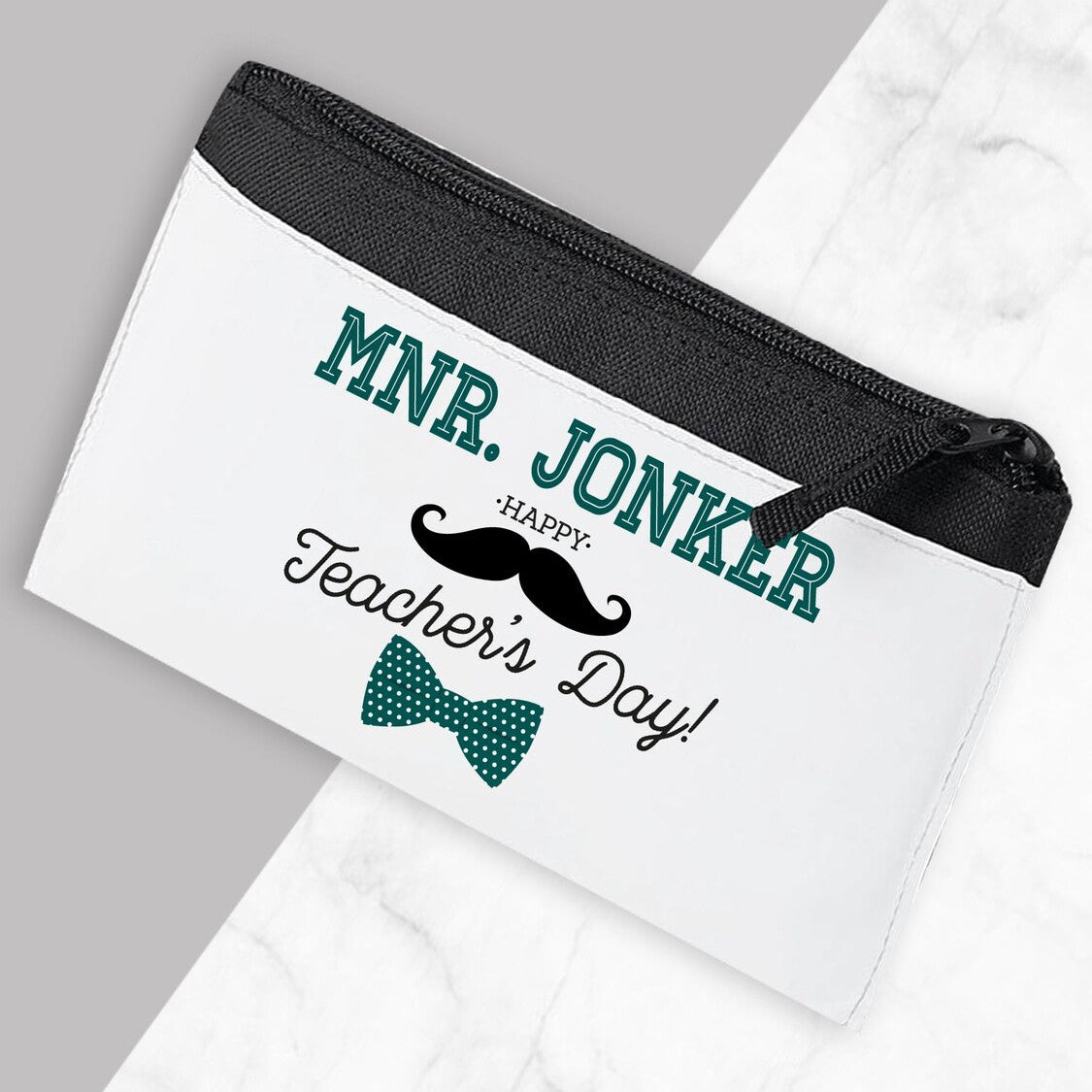 White pouch with black zipper and personalized text on a gray background