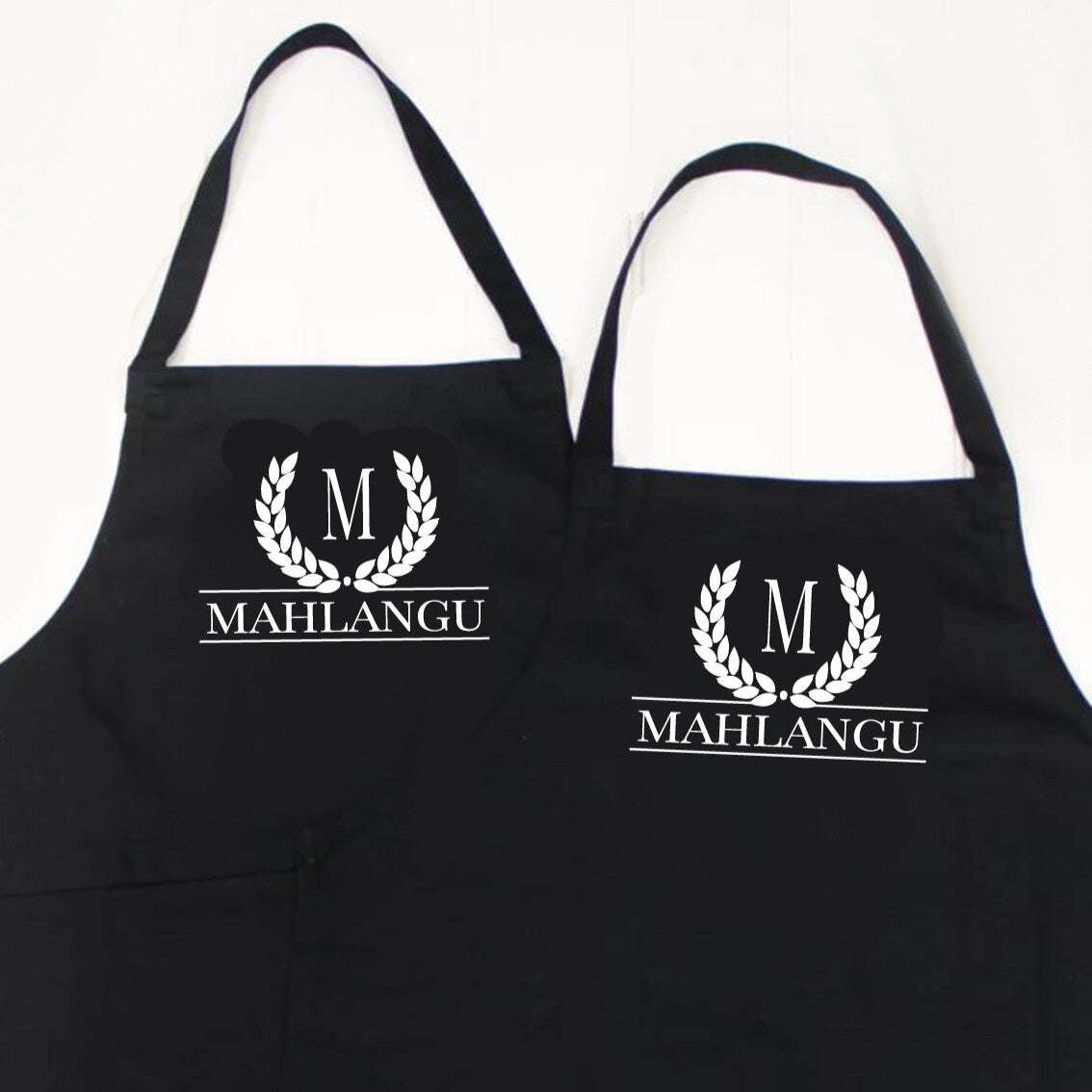 Personalised Couples Apron Set from Happy Look | South Africa – Stylish monogram design with "M" and "Mahlangu." Perfect for housewarmings and anniversaries, customisable with names. A thoughtful gift that brings joy and lasting memories. Shop now!