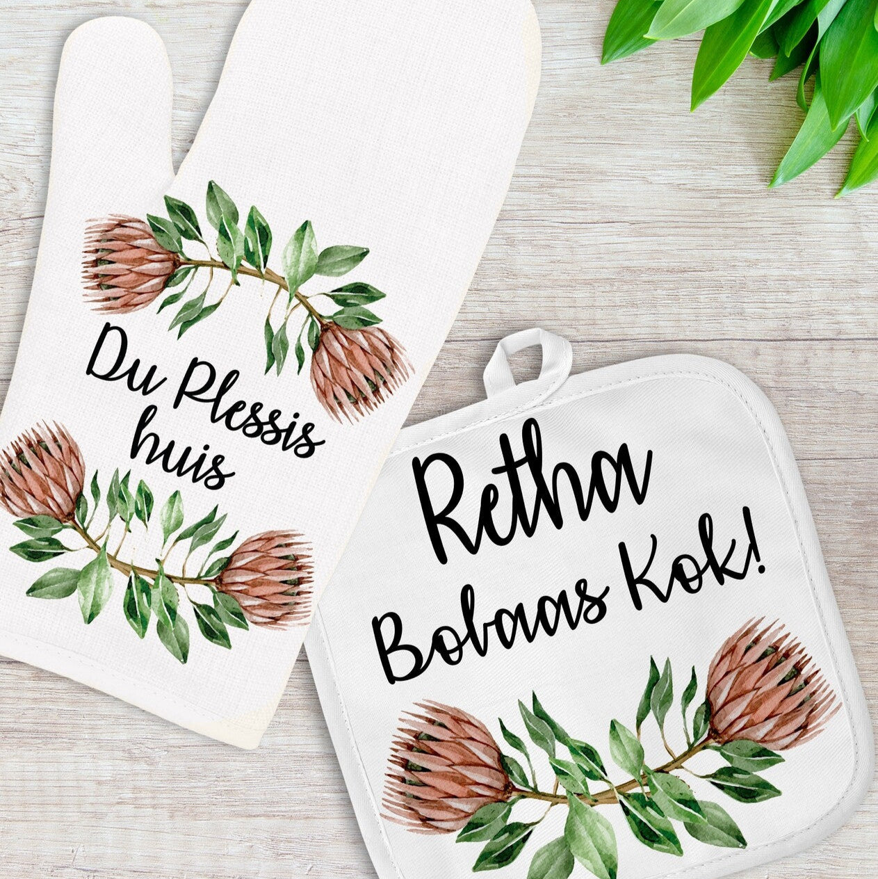Personalised Oven Mitt and Pot Holder Set from Happy Look | South Africa – Showcasing a beautiful protea design with customizable names. Perfect for Housewarming gifts and suitable for everyday use. A thoughtful gift that brings joy and lasting memories. Shop now!