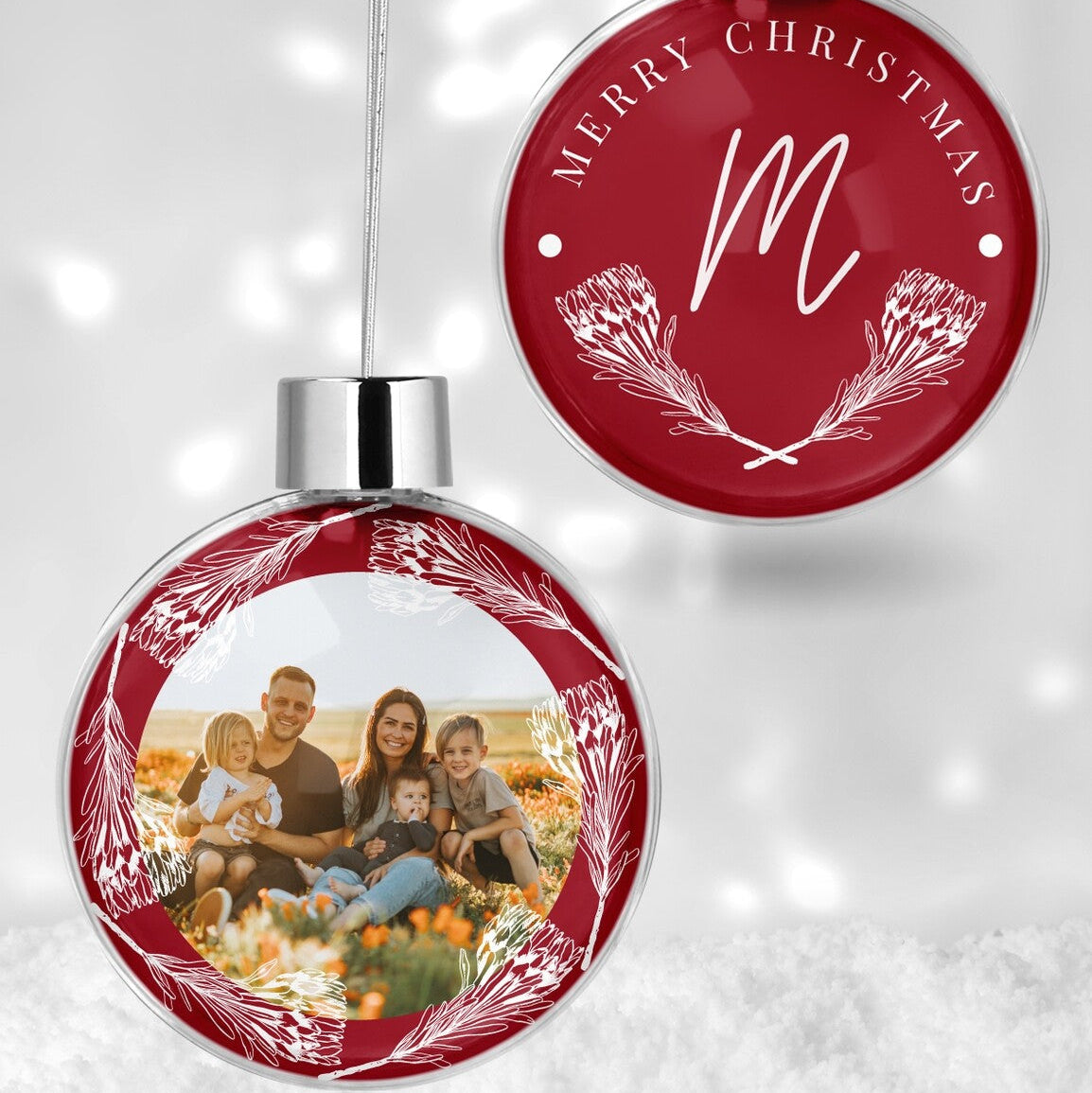 Custom Family Photo & Protea Christmas Bauble "Merry Christmas" from Happy Look | South Africa – A red Christmas bauble set. One bauble showcases a joyful family photo with white protea outlines, and the other features "MERRY CHRISTMAS," a script 'M', and a protea wreath design.
