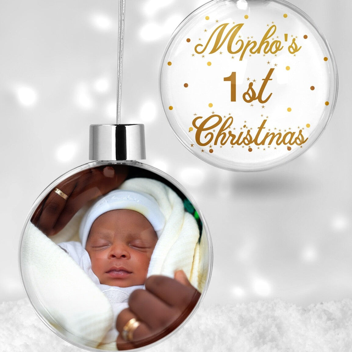 Custom "Mpho's 1st Christmas" Bauble from Happy Look | South Africa – A clear hanging Christmas bauble set. One bauble features a photo of a sleeping newborn baby, and the other displays "Mpho's 1st Christmas" in elegant gold script with stars.