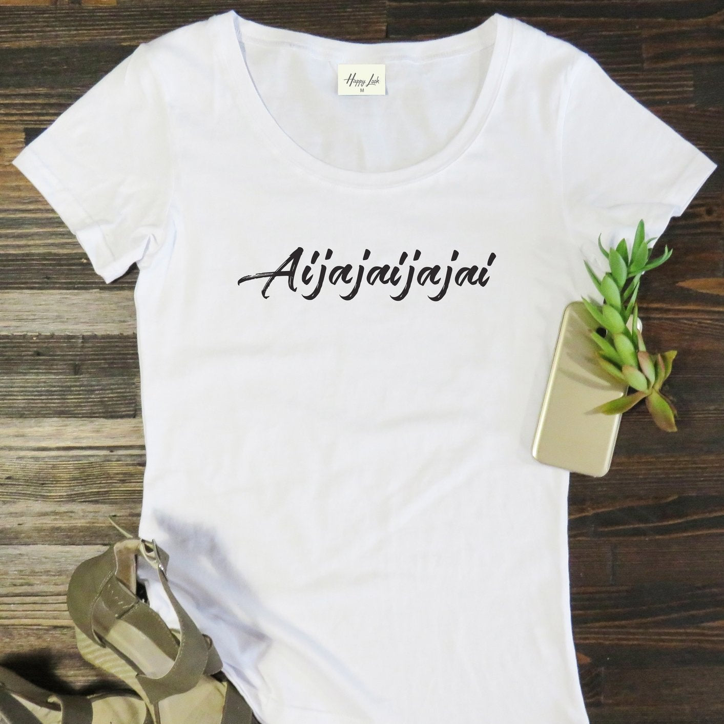 White South African-themed “Aijajai” t-shirt flat lay on wooden background. Fun and relatable local slang design printed on a premium-quality cotton tee by Happy Look, South Africa.
