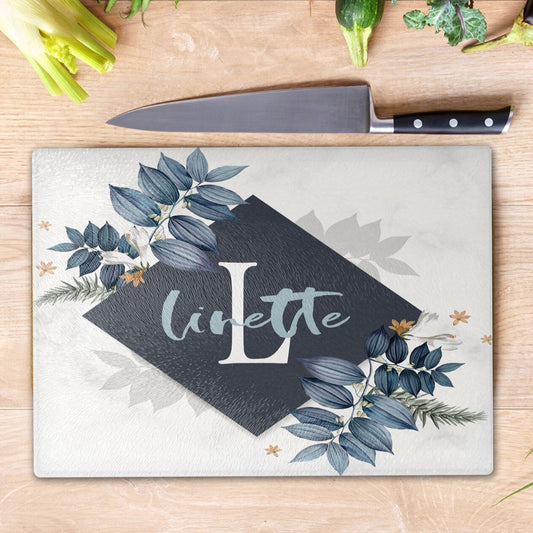 Personalised Glass Cutting Board from Happy Look | South Africa – Elegant glass cutting board featuring the name "Linette" and a large "L," beautifully adorned with blue leaves and golden accents. Perfect for birthdays, weddings, or housewarmings and customisable with a name or special message. A thoughtful gift that brings joy and lasting memories. Shop now!