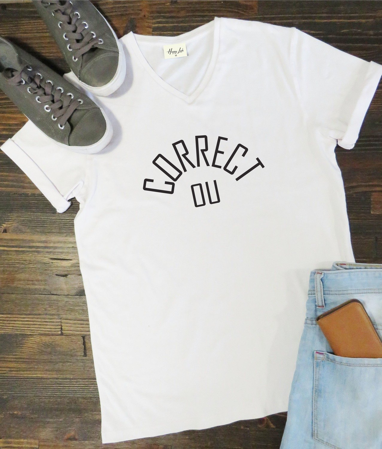 White t-shirt with 'CORRECT DU' text on a wooden surface with shoes and jeans.