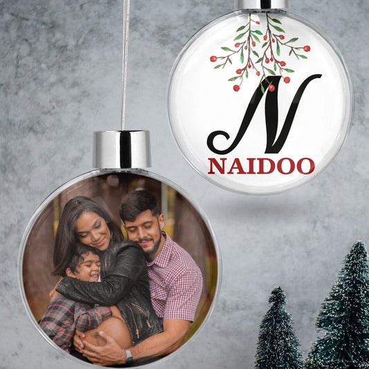 Custom Photo & Initial Christmas Bauble "N Naidoo" from Happy Look | South Africa – A clear hanging Christmas bauble set. One bauble features a loving family photo, and the other displays a large black initial 'N' and "NAIDOO" in red, with a festive branch design.