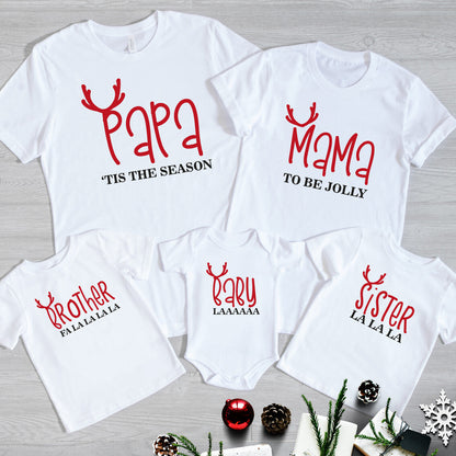 Family Christmas Matching T-Shirts from Happy Look | South Africa – White t-shirts and baby grow with playful red reindeer antler designs and festive sayings: “Papa ’Tis the Season,” “Mama To Be Jolly,” “Brother Fa La La La La,” “Sister La La La,” and “Baby Laaaaaa.” A fun and joyful Christmas outfit set for the whole family, perfect for festive celebrations and memorable holiday photos.