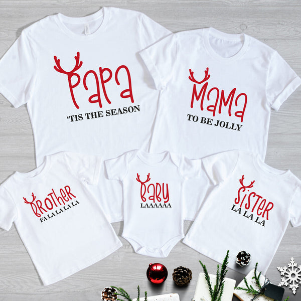 Family Christmas Matching T-Shirts from Happy Look | South Africa – White t-shirts and baby grow with playful red reindeer antler designs and festive sayings: “Papa ’Tis the Season,” “Mama To Be Jolly,” “Brother Fa La La La La,” “Sister La La La,” and “Baby Laaaaaa.” A fun and joyful Christmas outfit set for the whole family, perfect for festive celebrations and memorable holiday photos.