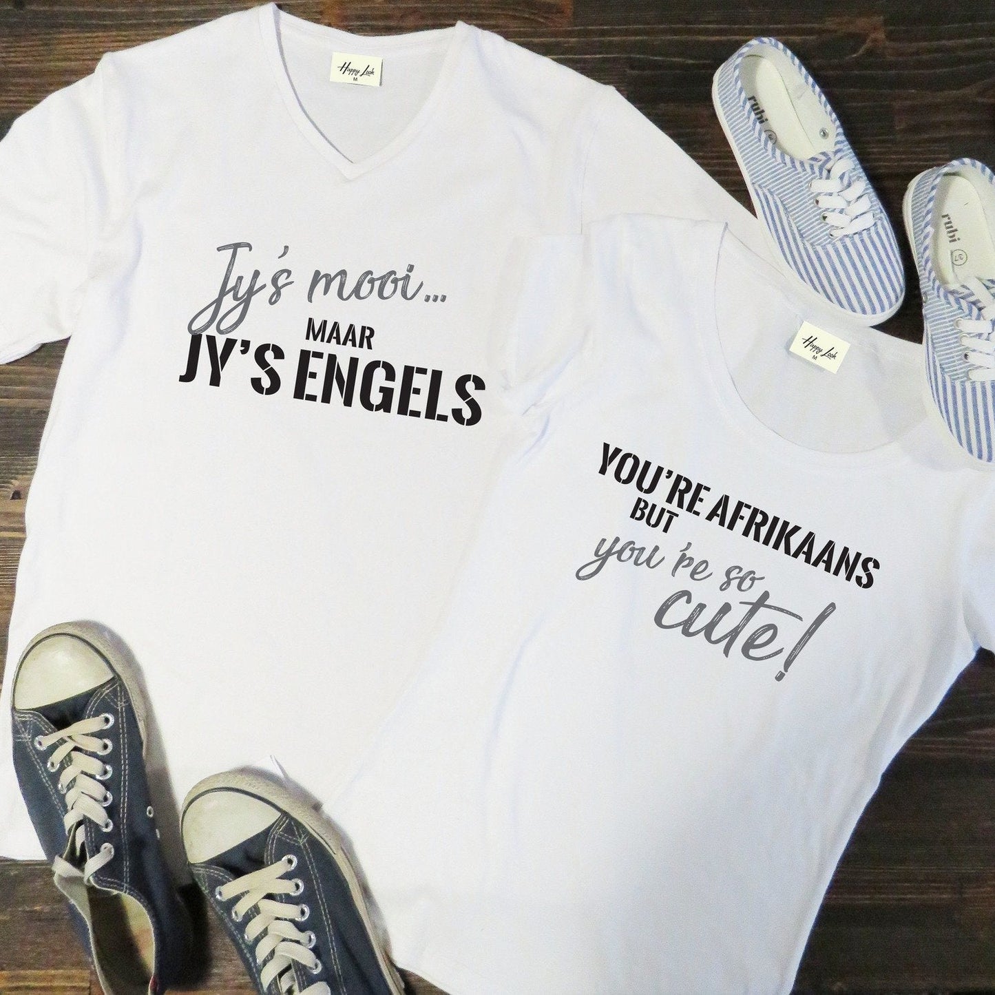 A matching couple’s T-shirt set with one shirt printed “Jy’s Mooi, Maar Jy’s Engels” and the other “You’re Afrikaans, But You’re So Cute.” Displayed side by side, the set playfully captures the charm of a bilingual love story.
