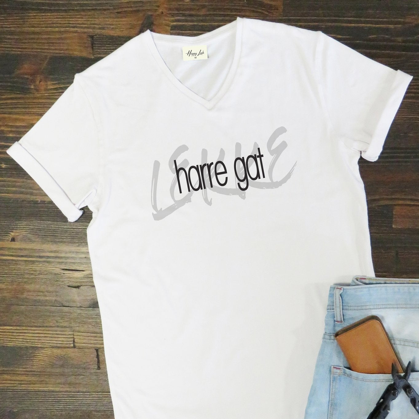 White t-shirt with text on a wooden surface with jeans and wallet.