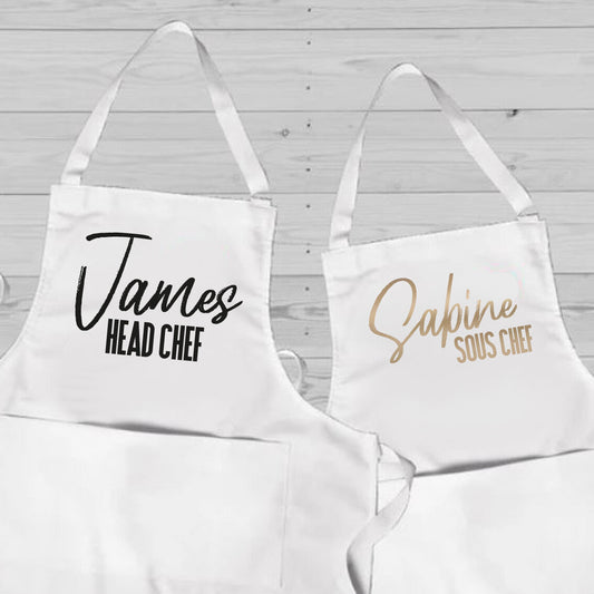 Personalised Couples Apron Set from Happy Look | South Africa – Professional chef-themed design, featuring "James" as Head Chef and "Sabine" as Sous Chef. Perfect for culinary enthusiasts and special occasions, customisable with names. A thoughtful gift that brings joy and lasting memories. Shop now!