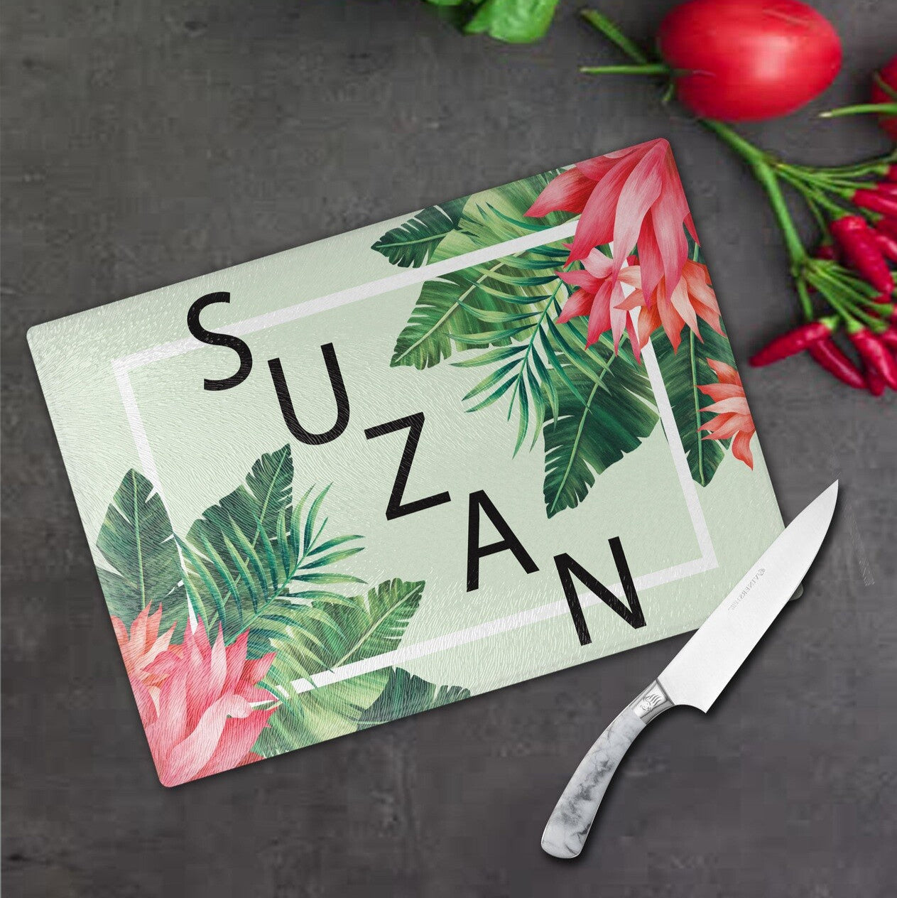 Personalised Glass Cutting Board from Happy Look | South Africa – A personalised cutting board featuring the name "SUZAN" surrounded by vibrant tropical leaves and flowers. Perfect for birthdays, housewarmings, or special occasions and customisable with a name or personal message. A thoughtful gift that brings joy and lasting memories. Shop now!